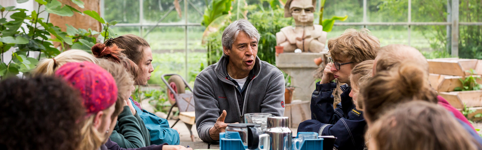 Docent geeft les aan een groep studenten in een kas.  