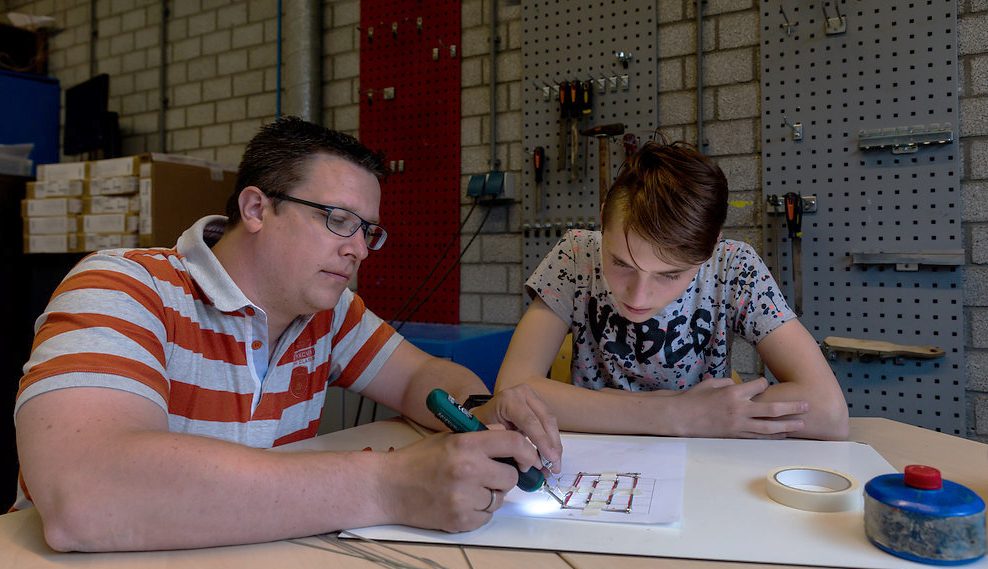 Docent geeft begeleiding aan leerling over Robotica